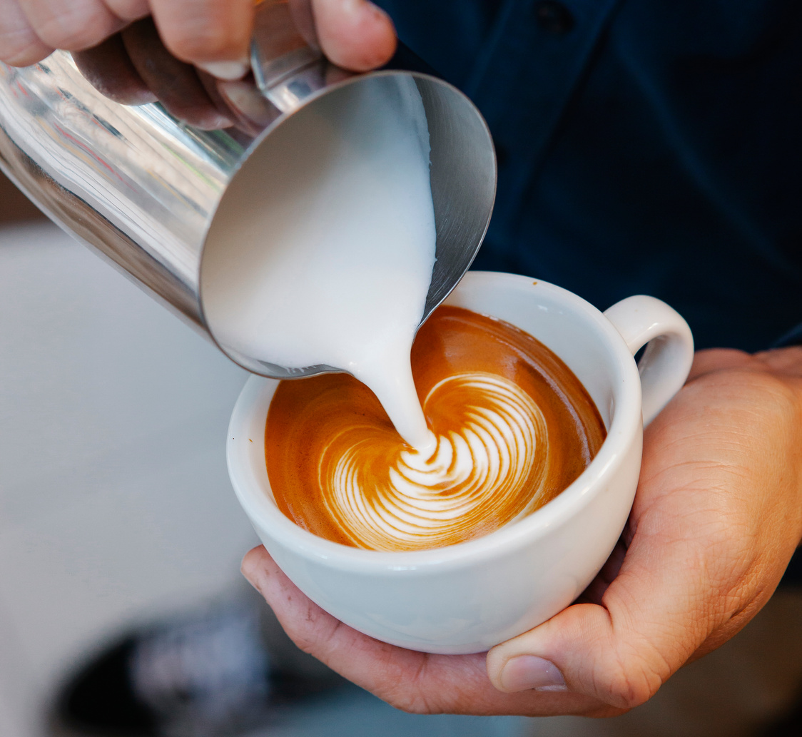 Faceless barista preparing delicious latte in coffee house